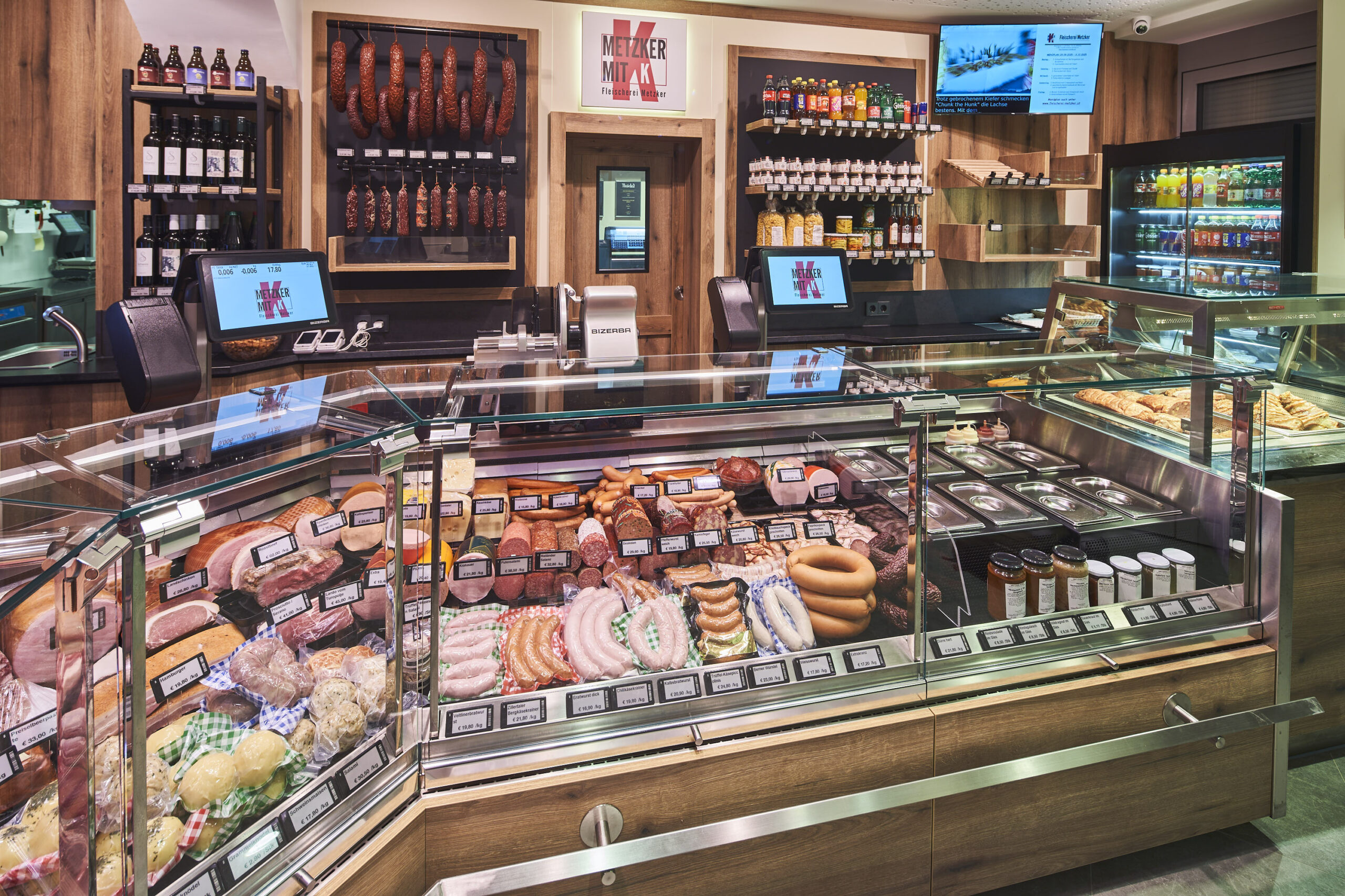 Das Sortiment reicht von Rind, Schwein und Geflügel bis zu hausgemachten Wurst- und Feinkostprodukten. Durchdachte Beleuchtung und Kühlung sorgen für appetitliche Präsentation und Energieeffizienz.