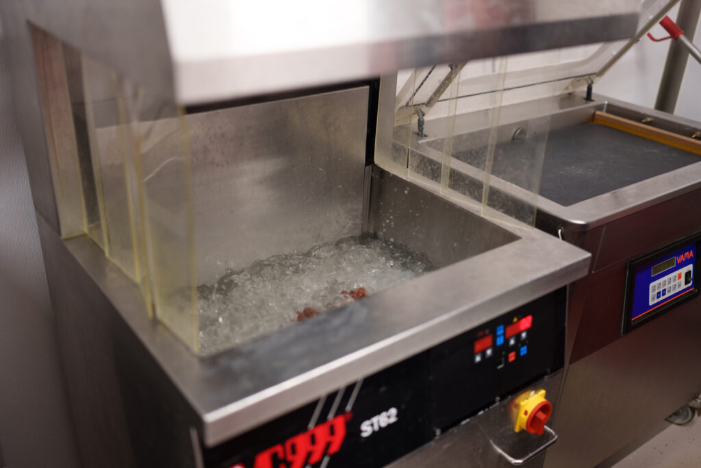 Eiswasser-Abschrecken der Würste nach dem Brühen an einer Kühlstation von VC999 zur Stabilisierung von Biss- und Produktqualität.© Henry Gasselich